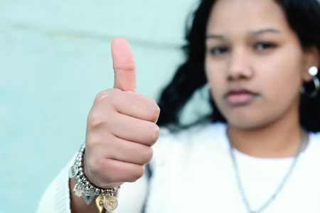 Portrait of beautiful latin teen girl doing thumbs up symbol. Outdoorsの写真素材