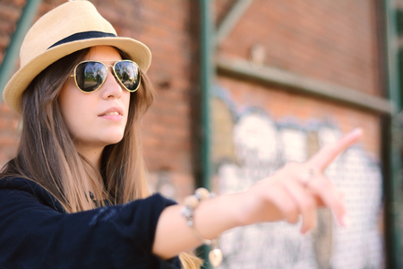 Young tourist woman in hat pointing finger somewhere. Travel concept. Outdoorsの写真素材