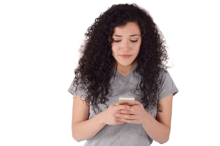 Young beautiful woman using her smartphone. Indoor. Isolated white background.の写真素材