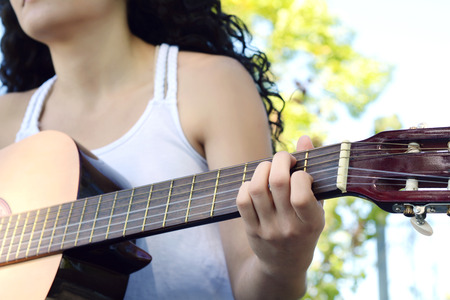 Closeup of young woman hands playing acoustic guitar at the park.の写真素材