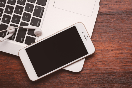 Close up view of keyboard and phone with black screen on wooden desk. Technology conceptの写真素材