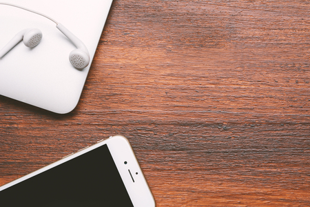 Close up view of mobile phone, laptop computer and white earphone with copyspace on wooden backgroundの写真素材