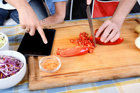 Couple cooking dinner using a digital tablet and smiling in kitchen at home. Relationship Conceptの写真素材