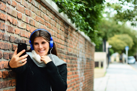 Portrait of a young beautiful woman taking selfie. Outdoors.の写真素材