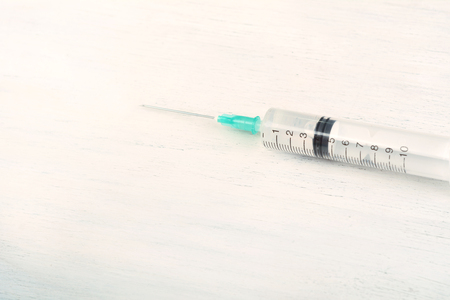 Close up view of medical syringe needle on white wooden background. Medicine conceptの写真素材