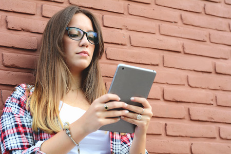Portrait of a young beautiful woman using her tablet. Outdoors. Urban scene.の写真素材