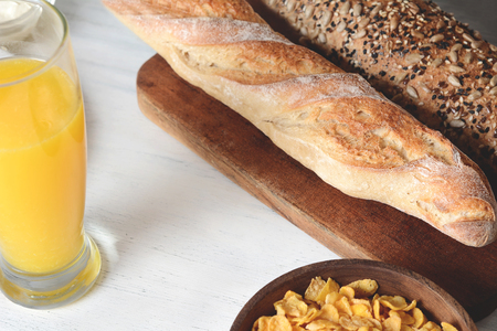 Healthy breakfast with bowl of cereal, orange juice and toast on white wooden background