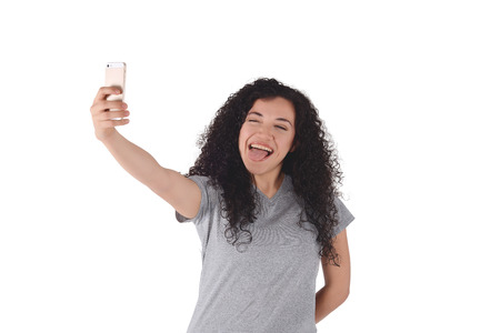 Young latin woman taking selfie with smartphone indoor. Isolated white background.