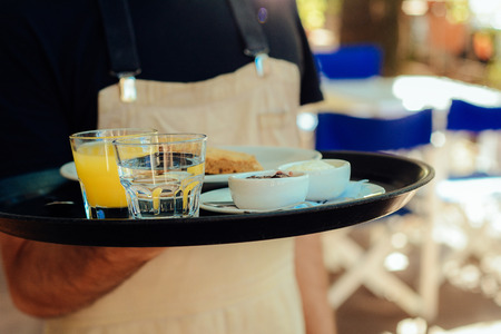 Close up young waiter holding tray at the coffee shop. Service conceptの写真素材