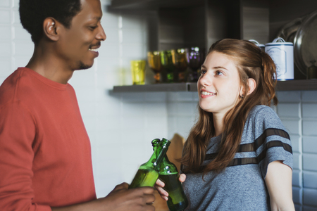 Young multi-ethnic friends having fun with bottles of drink at home. Friendship conceptの写真素材