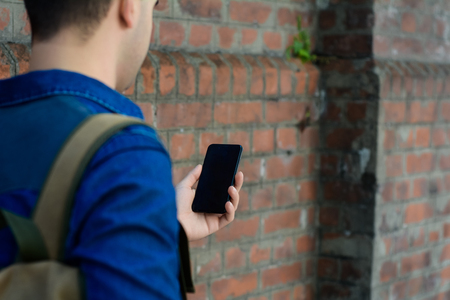 Portrait of young latin man typing on his phone. Outdoors.の写真素材
