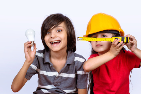 Portrait of little boy with holding a light bulb and a little girl wearing yellow construction helmetの写真素材