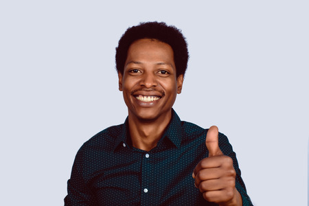 Portrait of Afro American man looking at camera showing thumbs up on studio.