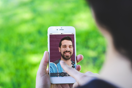 Closeup of woman chatting online by making video call on smartphone with her friend. Social media concept. All screen graphics are made up by usの写真素材
