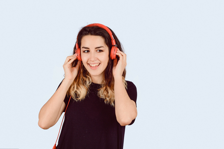 Beautiful young girl listening to music with red headphones in studio.の写真素材