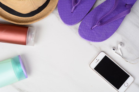 Close-up of a smartphone, flip flops, sunscreen and a hat. Travel concept.の写真素材