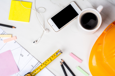 Close-up of blueprints, measuring tape, cup of coffee and yellow construction helmet. Engineer conceptの写真素材