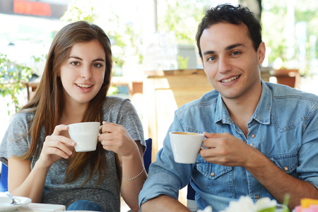 Young attractive couple enjoying a coffee at the coffee shop. Outdoors.の写真素材