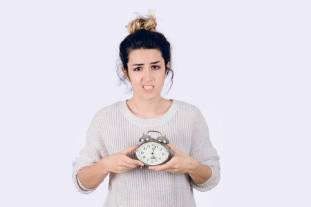 Young woman with alarm clock. Isolated over white background.