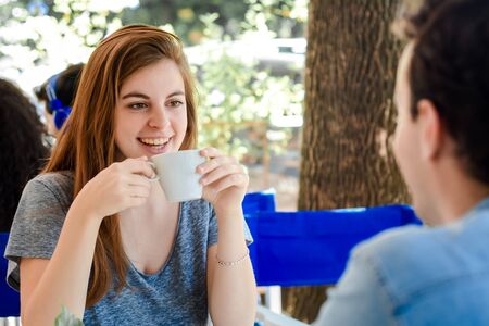 Young attractive couple enjoying a coffee at the coffee shop. Outdoors.の写真素材