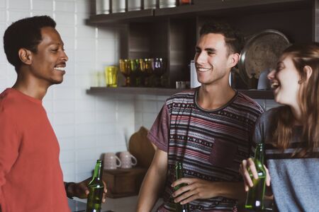 Young multi-ethnic friends having fun with bottles of drink at home. Friendship conceptの写真素材
