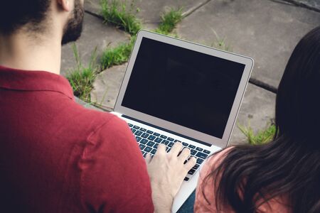 Portrait of Young male student using laptop and learning online outdoor.の写真素材