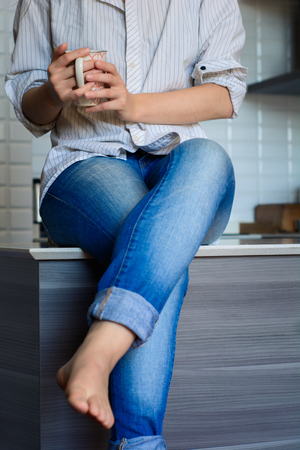 Pretty young woman drinking coffee in kitchen at homeの写真素材
