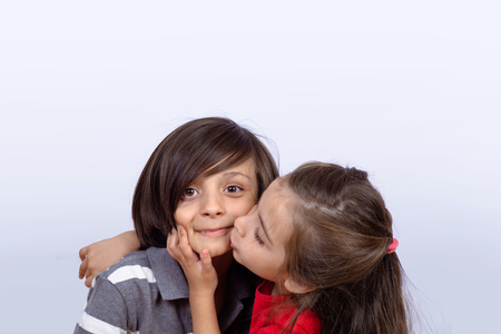 Portrait of brothers. Little girl kissing little boy face on studio.の写真素材