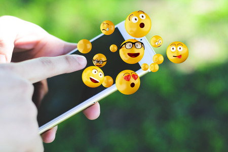 Close-up of woman using smartphone sending emojis. Social concept.の写真素材