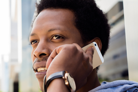 Portrait of young black man talking on mobile phone outside.の写真素材