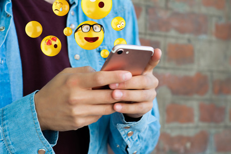 Close-up of man using smartphone sending emojis. Social concept.の写真素材