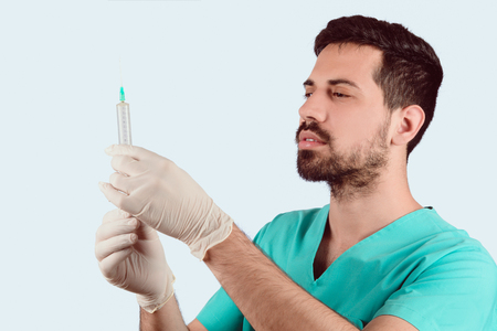 Portrait of Young doctor holding syringe for injection. Isolated on white background.の写真素材