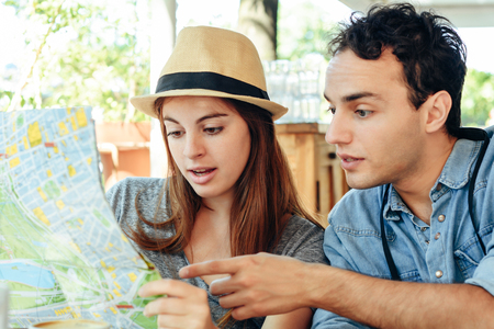 young tourist couple are looking at a map in a restaurant. Travel concept.の写真素材