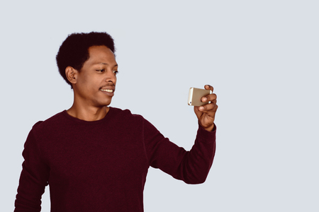 Portrait of Afro American man taking selfie with mobile phone on studio.