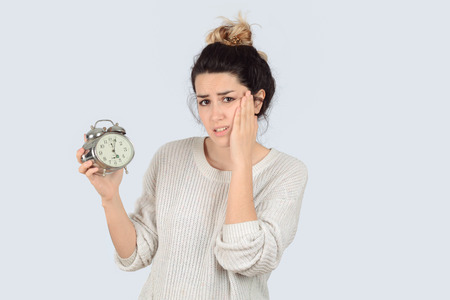 Young woman with alarm clock. Isolated over white background.