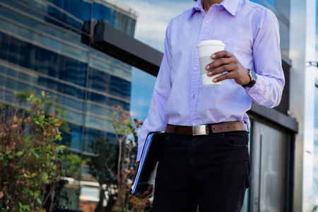 Portrait of young latin businessman holding coffee cup outside of office.の写真素材