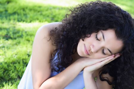 Young latin woman sleeping on the park. Rest and relaxation concept. Outdoorsの写真素材
