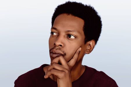 Portrait of Afro American thinking man with hand near face on studio.