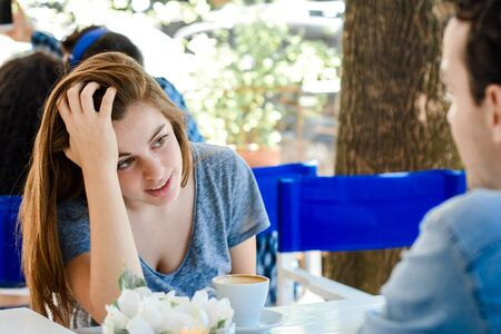 Young attractive couple enjoying a coffee at the coffee shop. Outdoors.