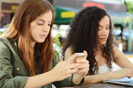 Friends using smartphone and laptop at coffee shop. Communication concept.の写真素材