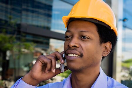 Professional man in helmet talking on the phone at street.の写真素材