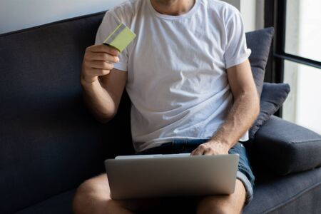 Young man with laptop computer and credit card at home. Shopping and lifestyle concept.の写真素材