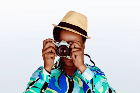 American tourist man taking photo with camera on white studio background. Travel concept.