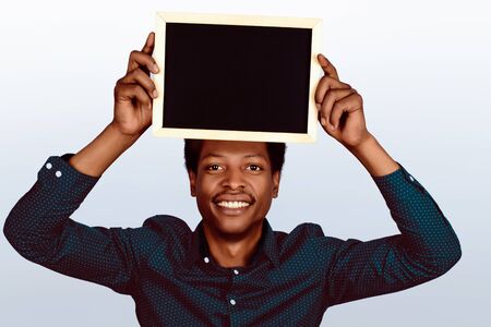 Portrait of american man holding chalkboard on studio background.