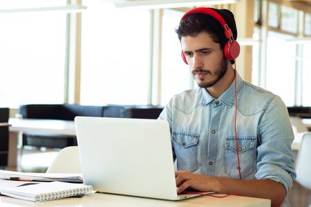 Portrait of Young male student using laptop and learning online in the university library.の写真素材
