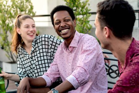 Group of young multi-ethnic friends with pizza and bottles of drink celebrating at outdoor rooftop. Friendship conceptの写真素材