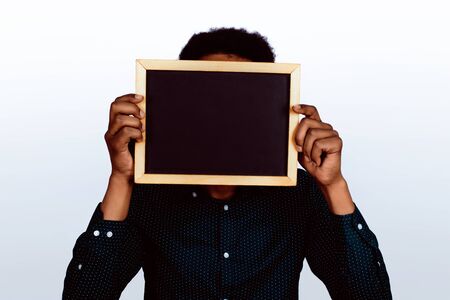 Portrait of american man holding chalkboard on studio background.の写真素材