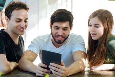 Group of friends using digital tablet and enjoying together in a coffee shop.