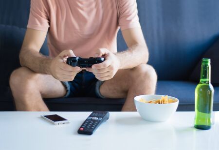Portrait of young man playing video games in his living room. Technology and games concept.の写真素材