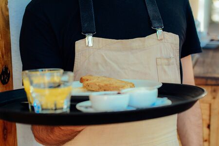 Close up young waiter holding tray at the coffee shop. Service conceptの写真素材